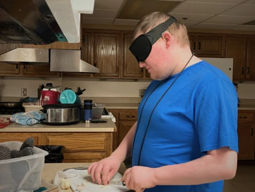 Boy in sleep shades chopping an onion in the kitchen