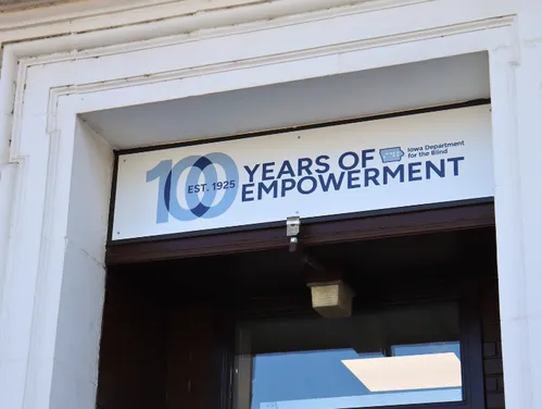 Sign reads “100 Years of Empowerment” for the Iowa Department for the Blind above a building entrance.