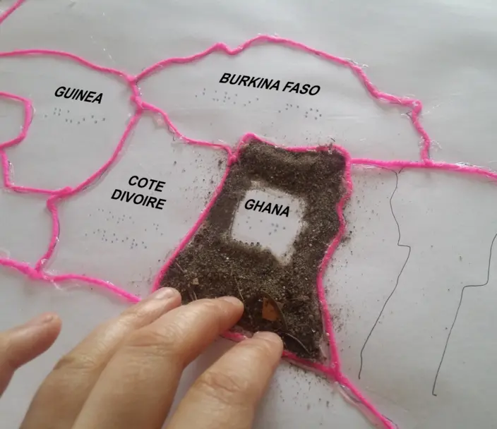 a tactile map of Africa with countries spelled in Braille, raised borders, and sandy texture on Ghana