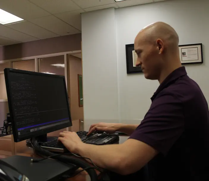 Man working at a desk with a braille display.