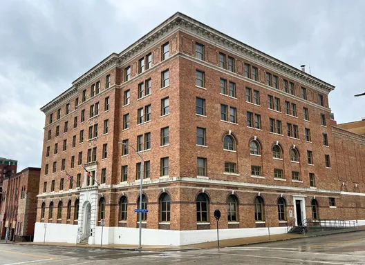 A large historic brick building with six floors on the corner of two streets