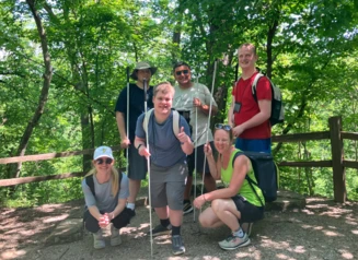 A group of LEAP students stand together and smile for a group photo during a hike